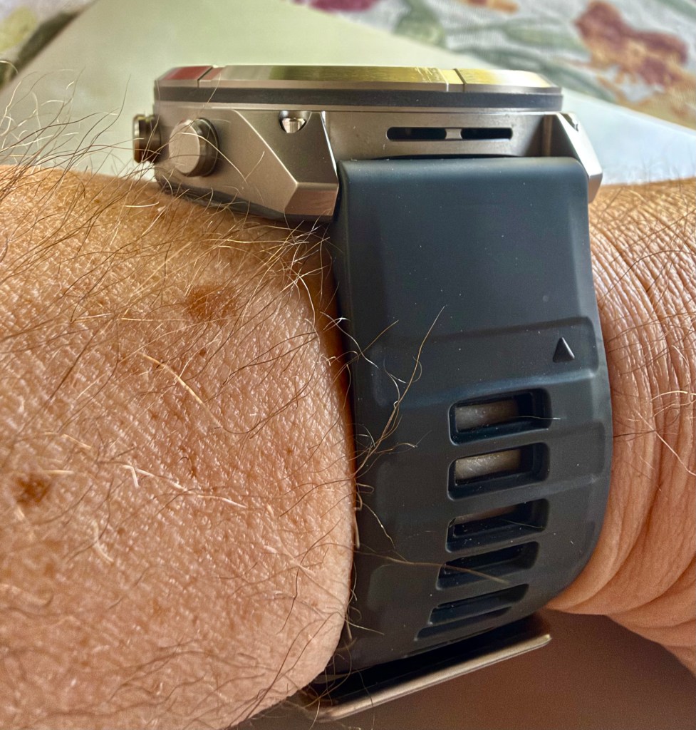 Close-up of a wrist wearing a stainless steel watch with a black silicone strap.